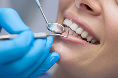 The image shows a person receiving dental care, with a dentist using a drill to work on their teeth.