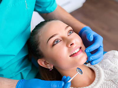 A dental professional is performing a teeth cleaning procedure on a patient in a dental office setting.